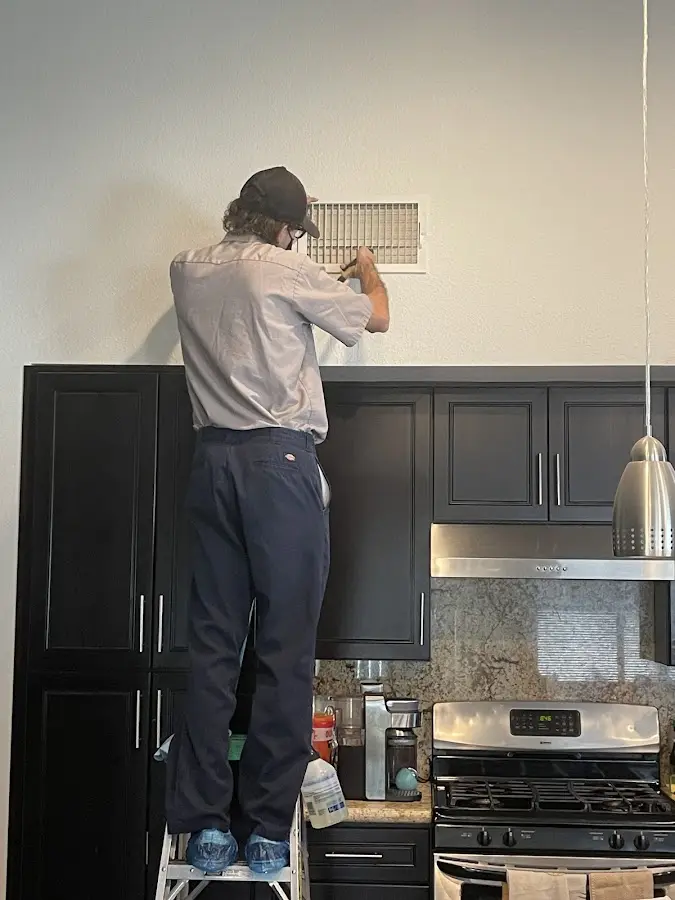 Technician inspecting an air vent during HVAC service in Hollins